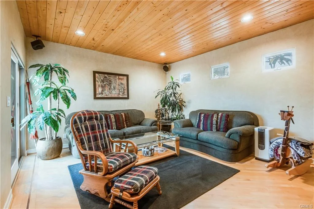 A living room with a sofa, chairs, coffee table, and plants.