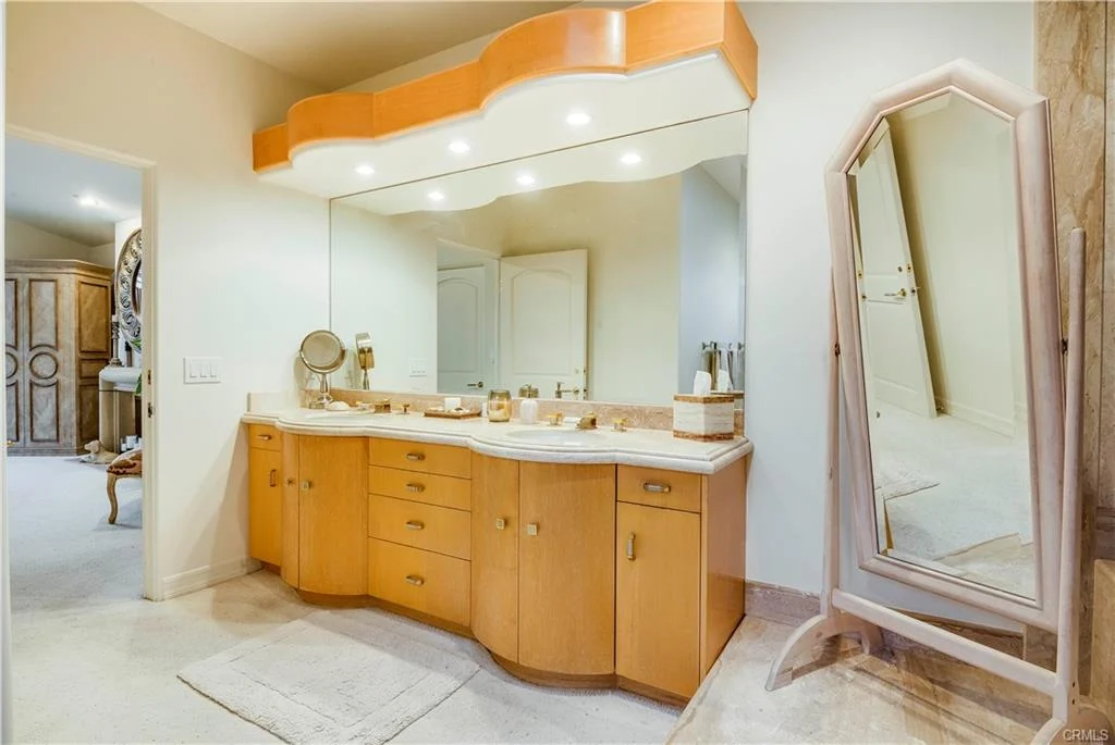 A bathroom with an orange vanity and mirrors.
