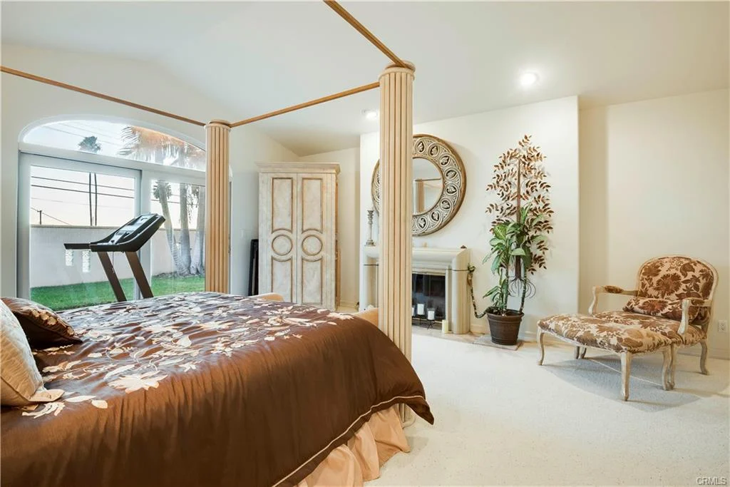 A bedroom with a large bed, plant, and armchair.