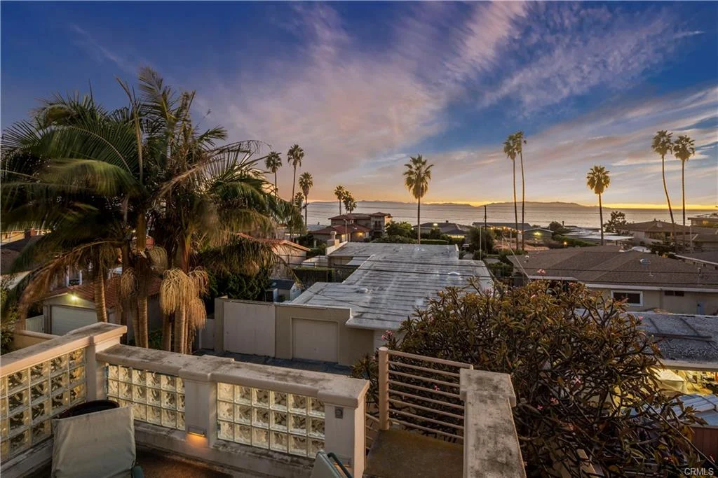 A balcony with palm trees and rooftops, real estate.