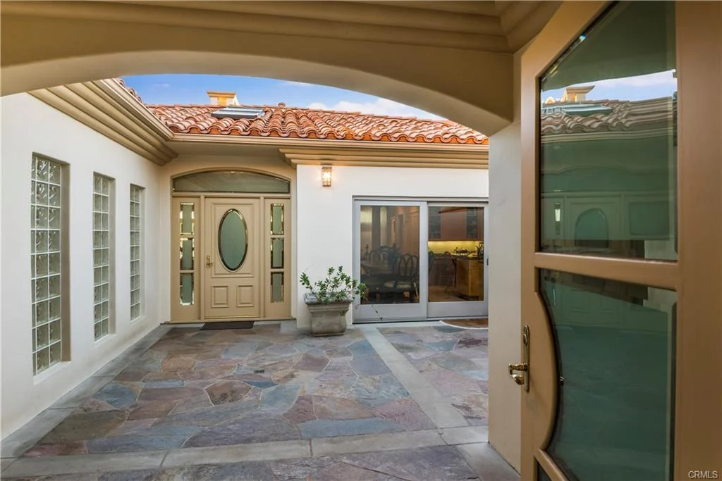 Entryway with door, windows, stone floor, and potted plant, house.