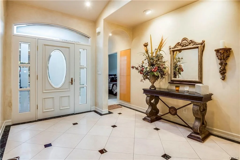 Entryway with front door, console table, mirror, and flowers.