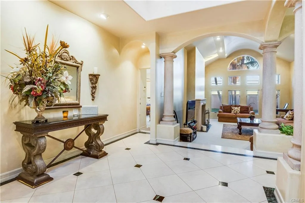 Entrance hall with console table, floral arrangement, and columns.
