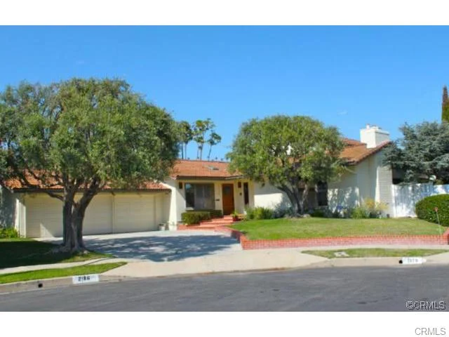 ouse with California real estate, a new roof, white exterior walls, and a yard with trees and a driveway.