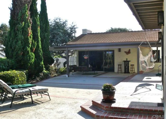 Patio with a hanging chair, lounge chairs, and potted plants.