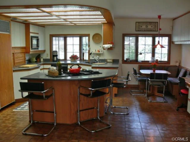 Large kitchen with a central island, bar stools, stainless steel appliances, and a dining area.