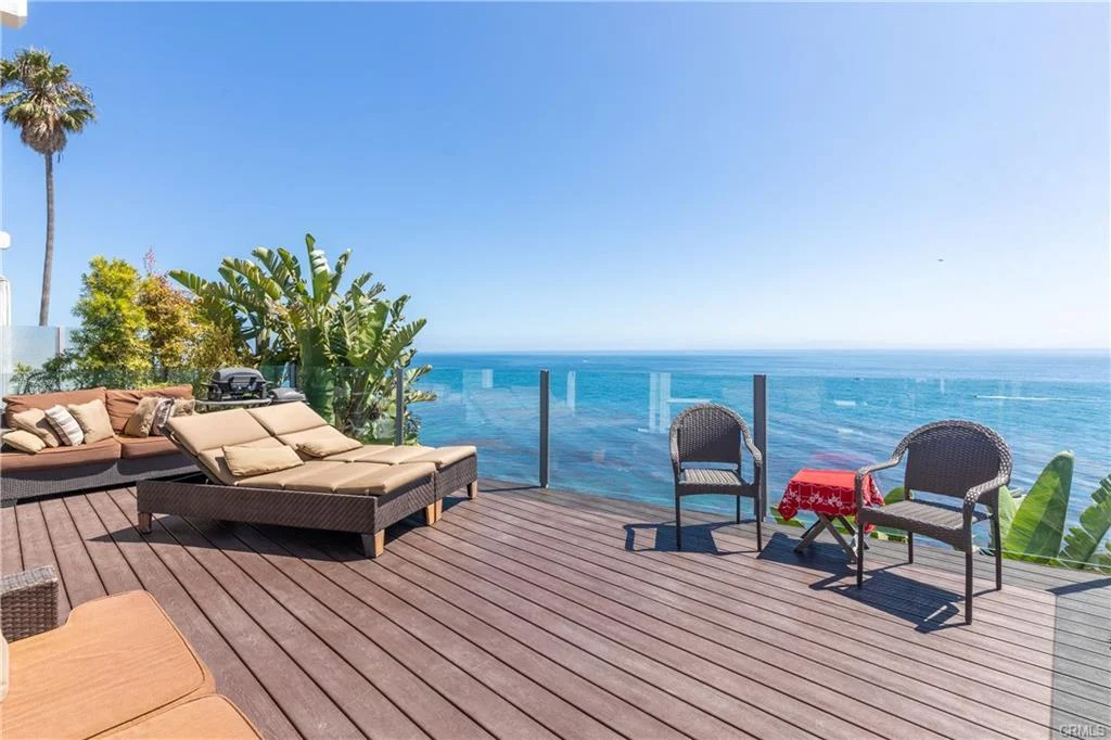 Deck with chairs, table, plants, and ocean view