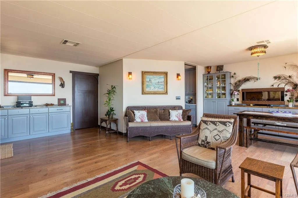 Living room with couch, chairs, dining table, wall art, and wooden floor