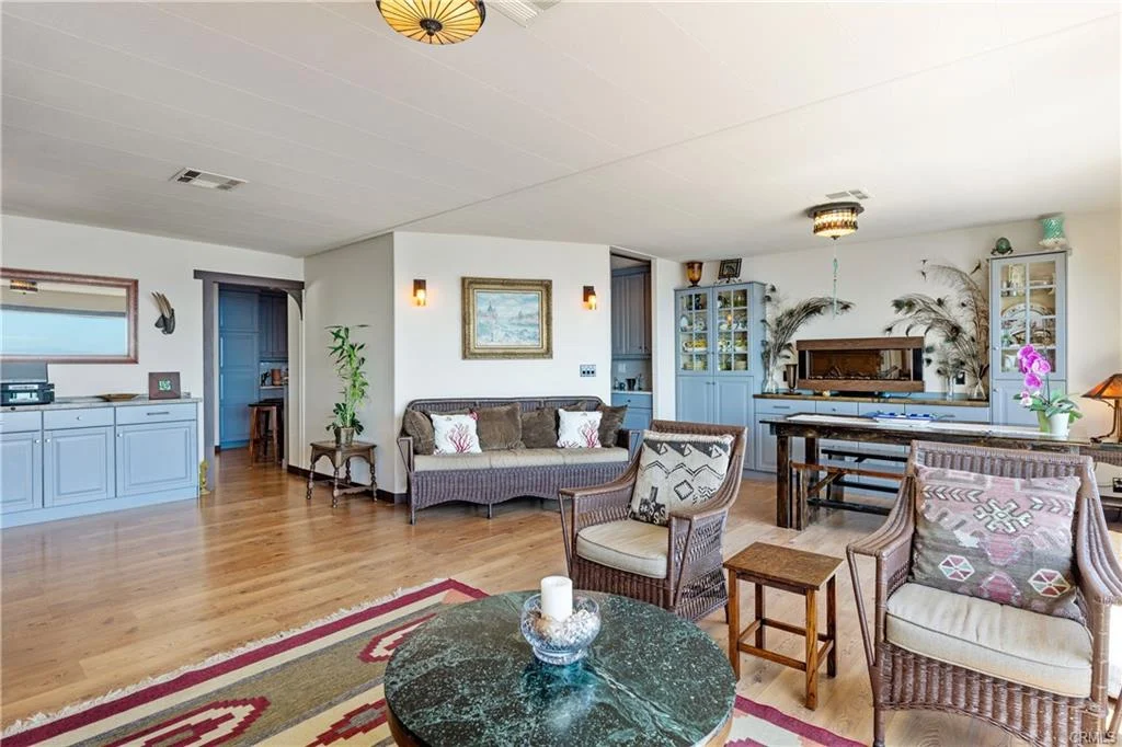 Living room with sofa, chairs, coffee table, plants, wall art, and dining area
