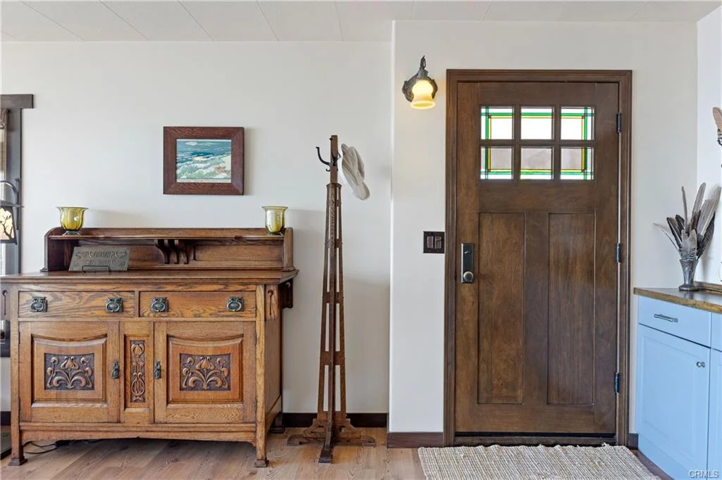 Entryway with wooden chest, coat rack, door with glass, and wood floor