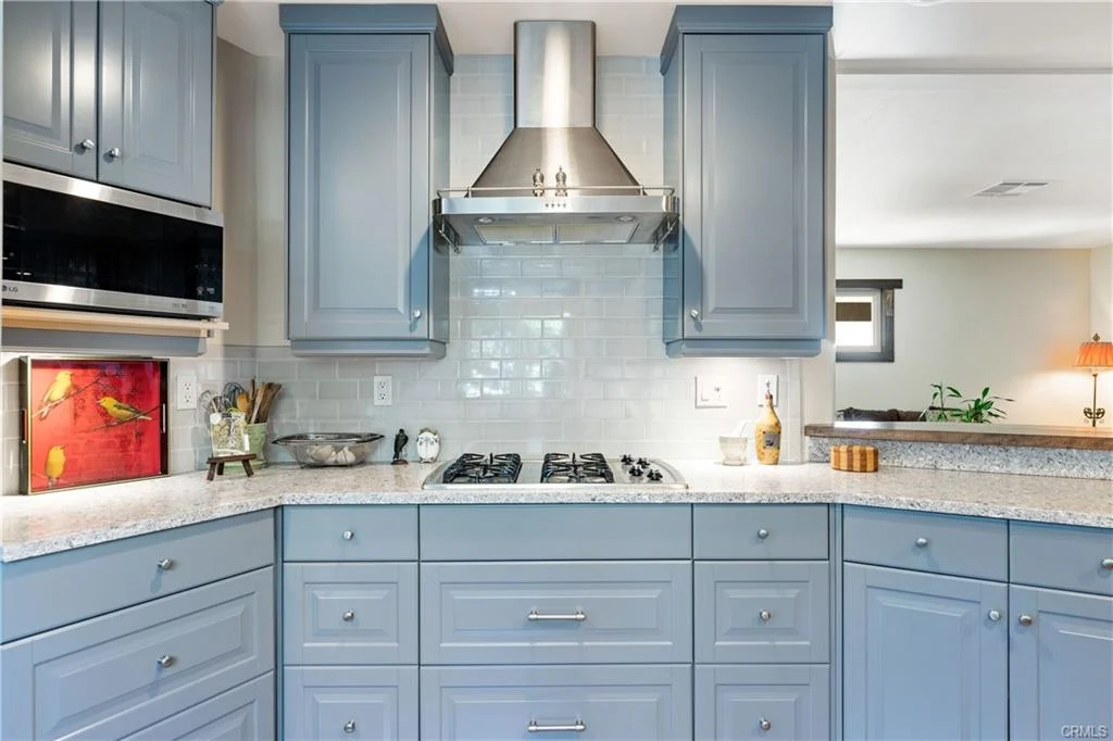 Kitchen with blue cabinets, range hood, gas cooktop, and built in oven