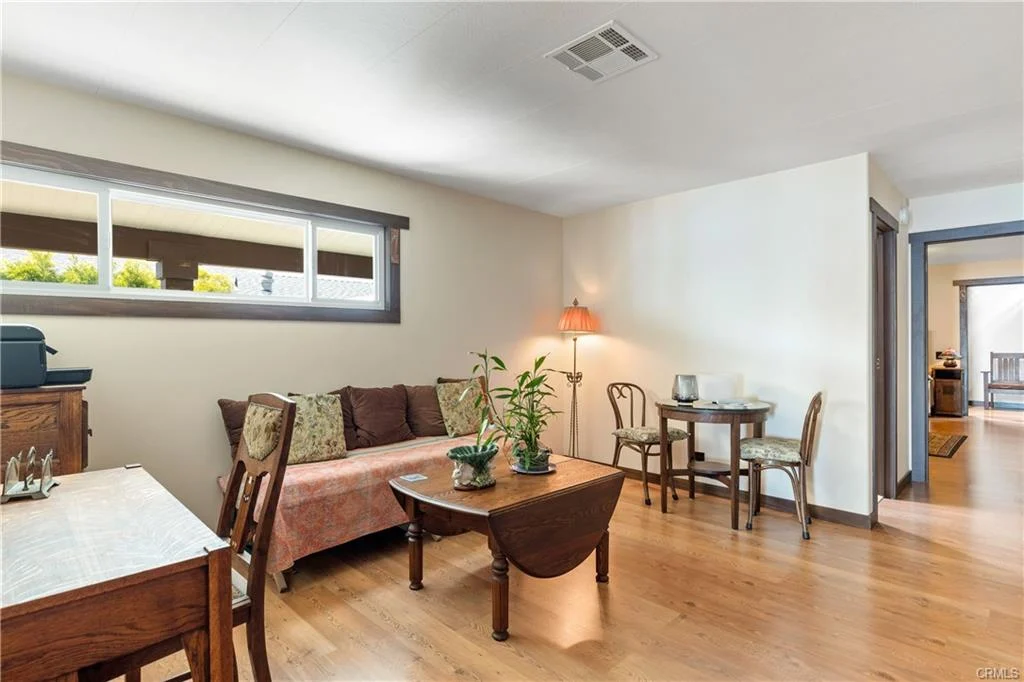Room with chairs, table, plants, and kitchen with bar stools