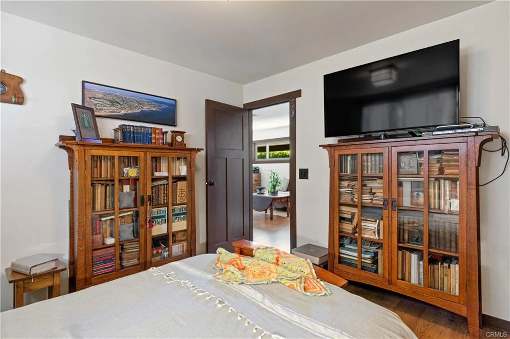 Bedroom with bed, bookshelves, TV, door, and decor