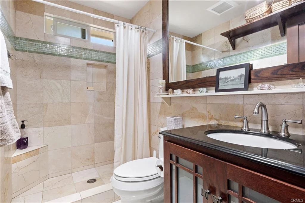 Bathroom with walk in shower, toilet, sink, mirror, and wooden cabinets