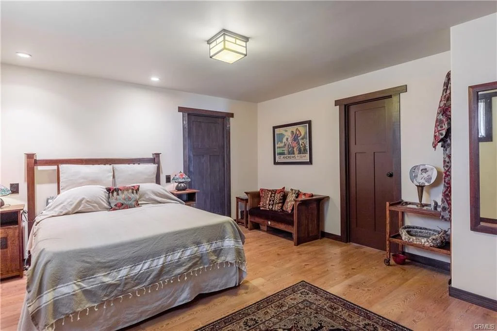 Bedroom with bed, wooden furniture, bench, and framed wall art