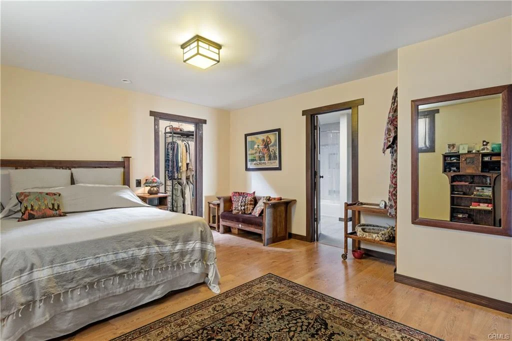 Bedroom with bed, bench, mirror, rug, and doors with wall art