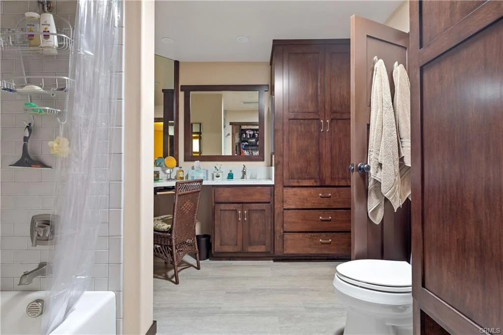 Bathroom with shower, toilet, wooden cabinets, and vanity