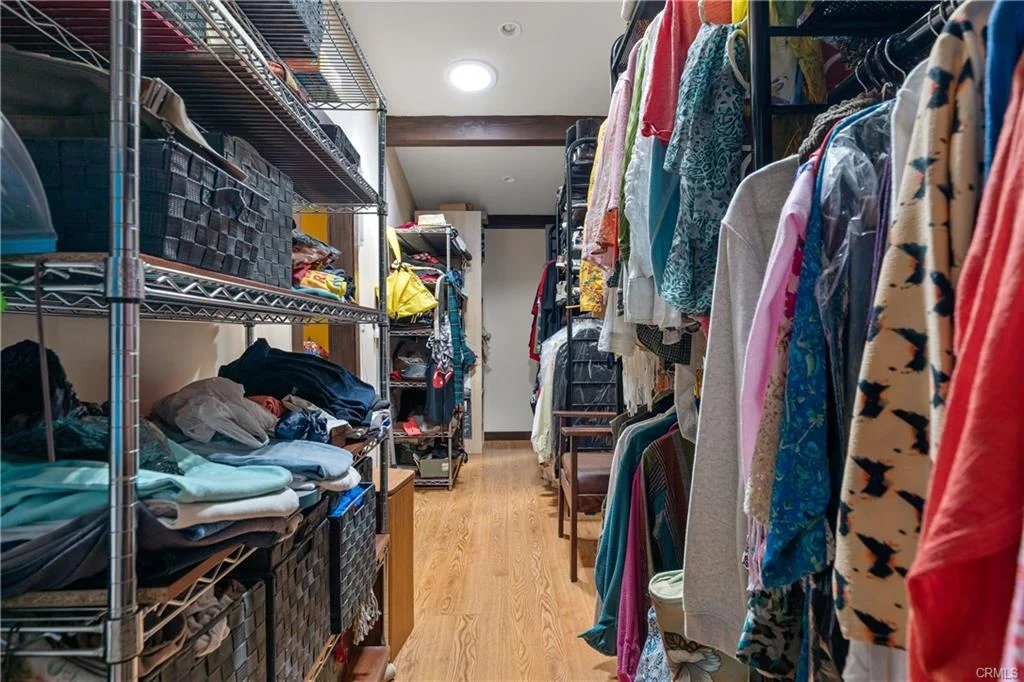 Hallway with shelves and clothes on both sides with wooden floor