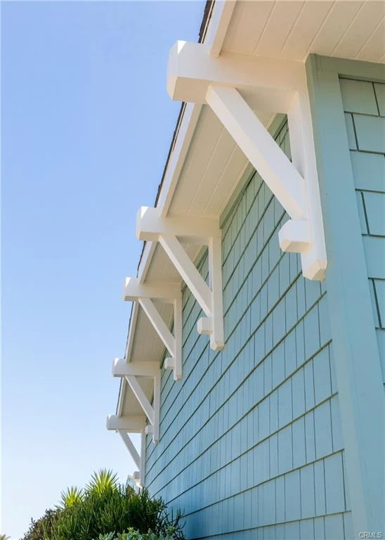 Close view of house eaves with white brackets on blue wall