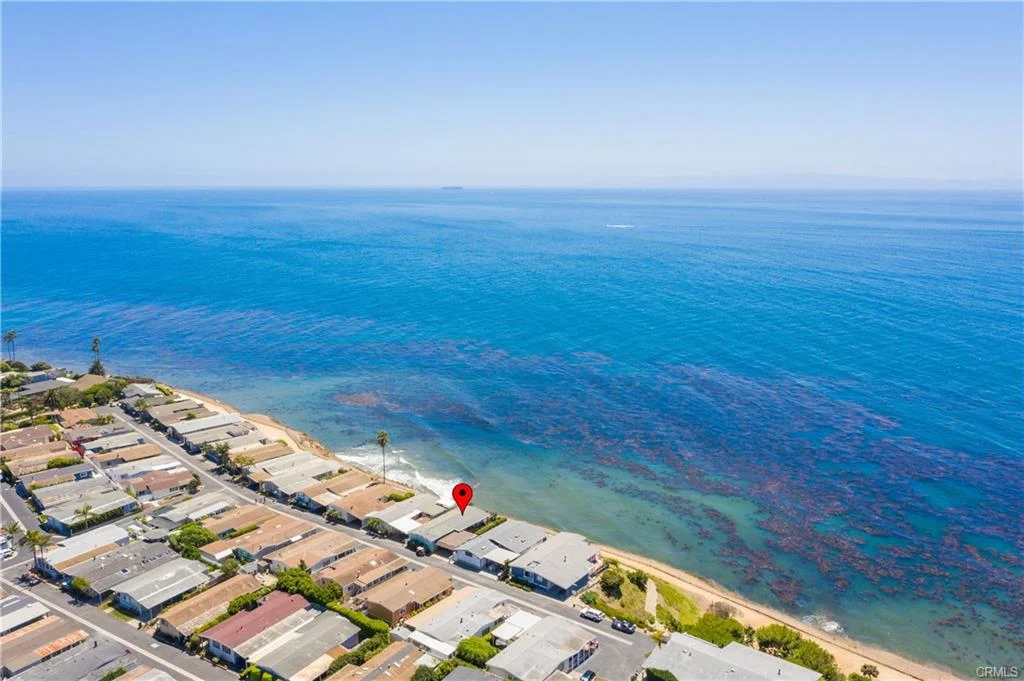 Aerial view of houses near shoreline with ocean in background