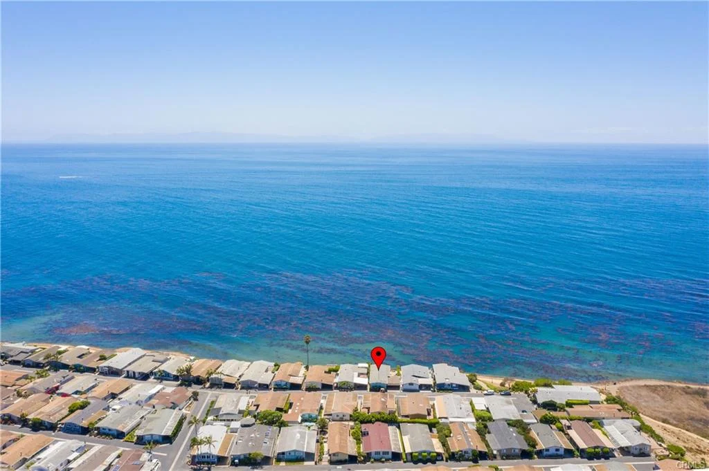 Aerial view of houses by ocean with location marker