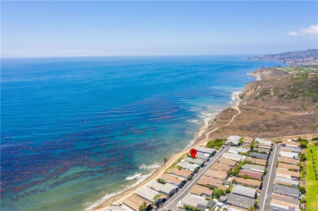 Aerial view of houses along shoreline with ocean and land in background