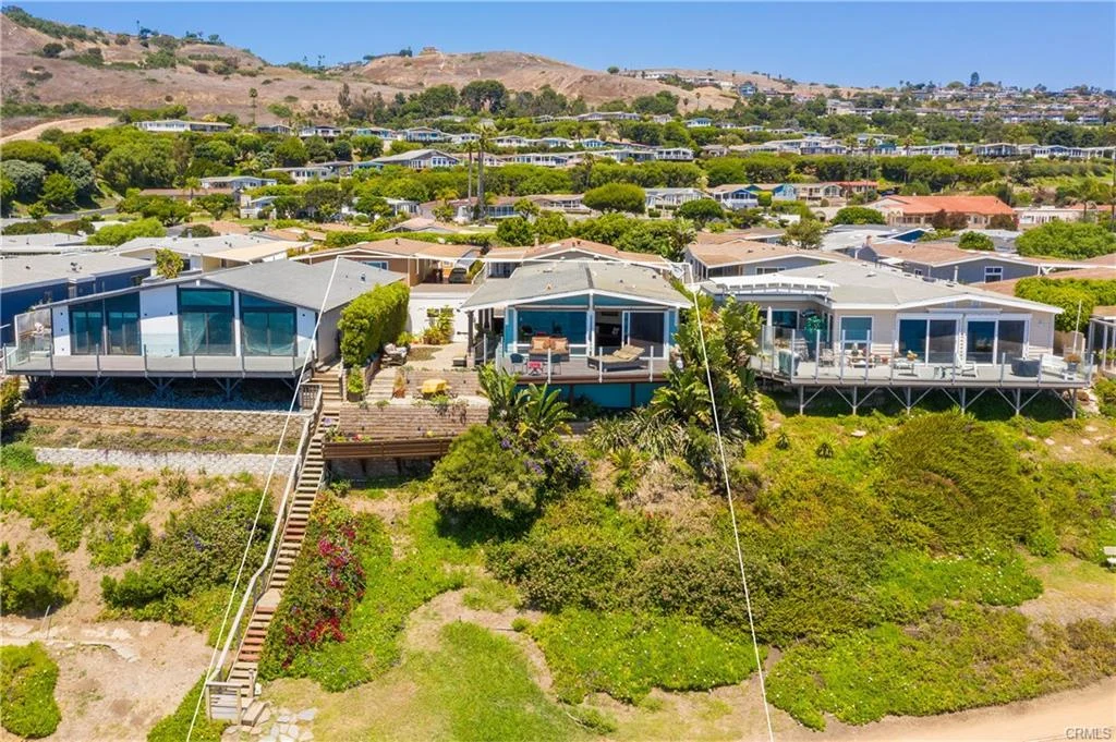 Aerial view of houses on hillside with greenery near coast