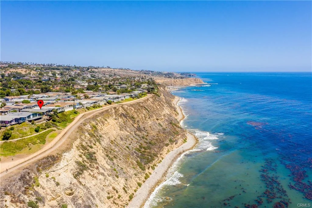 Aerial view of coastal cliffs with ocean and houses along the shoreline