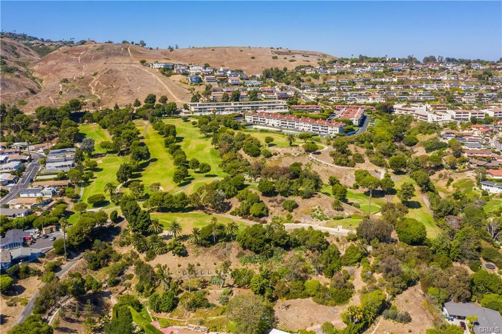 Aerial view of hills with golf course, houses, and green areas