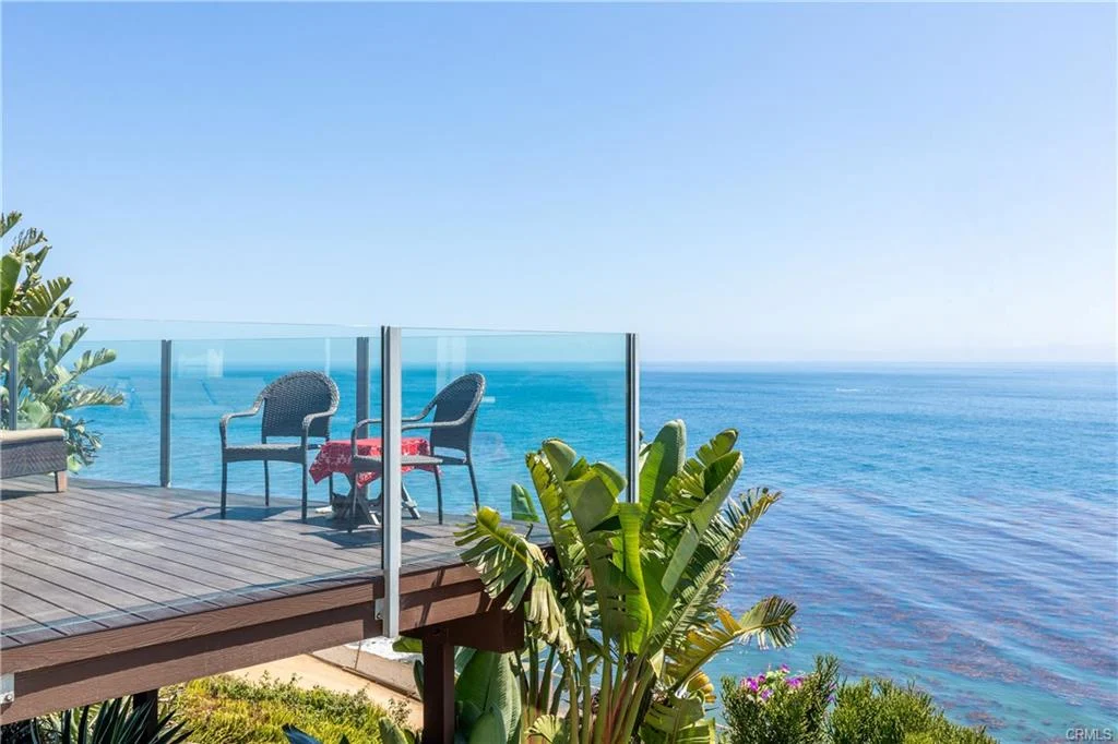 Deck with chairs, table, plants, and ocean view