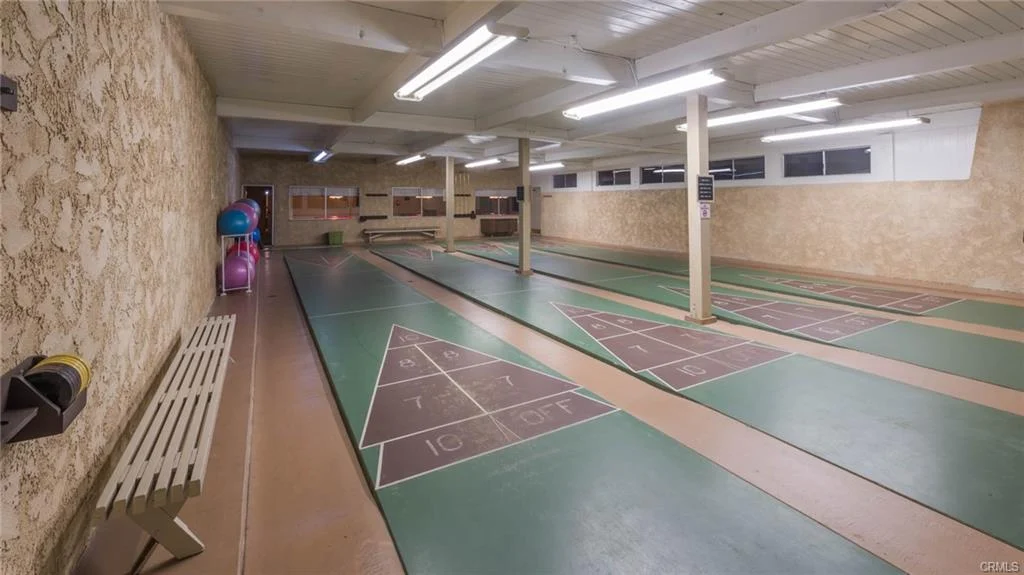 Game room with shuffleboard courts, balls, benches, and lights