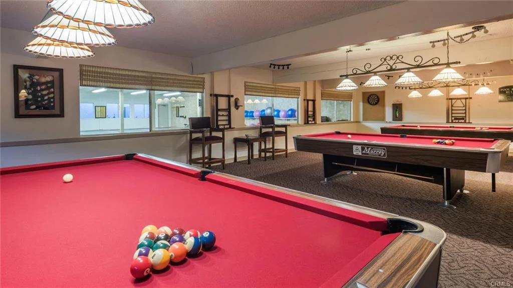 Pool table with red felt, balls, lamps, and windows