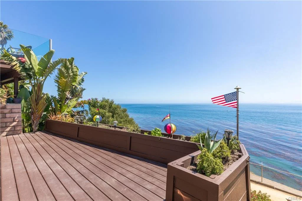 Deck with plants, flag, and ocean view near a house California real estate