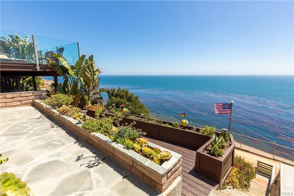 Deck with plants, flag, and ocean view near a house California real estate