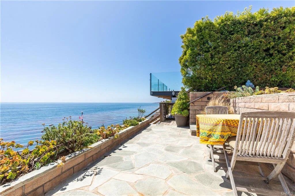 Patio with stone floor, wood furniture, and ocean view near a house California real estate