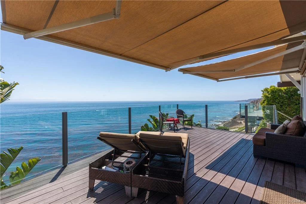 Deck with lounge chairs, umbrellas, greenery, and ocean view