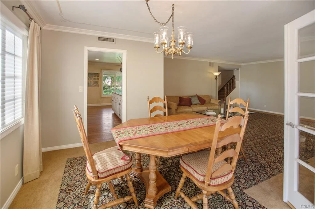 Dining area with wooden table, chairs, and chandelier.