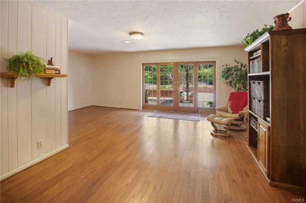Living room with hardwood floor, bookshelf, and sliding doors.
