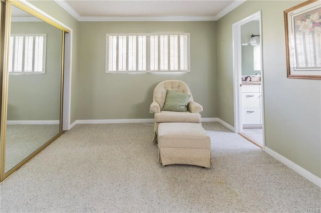 Living room with armchair, ottoman, mirror, and light green walls.