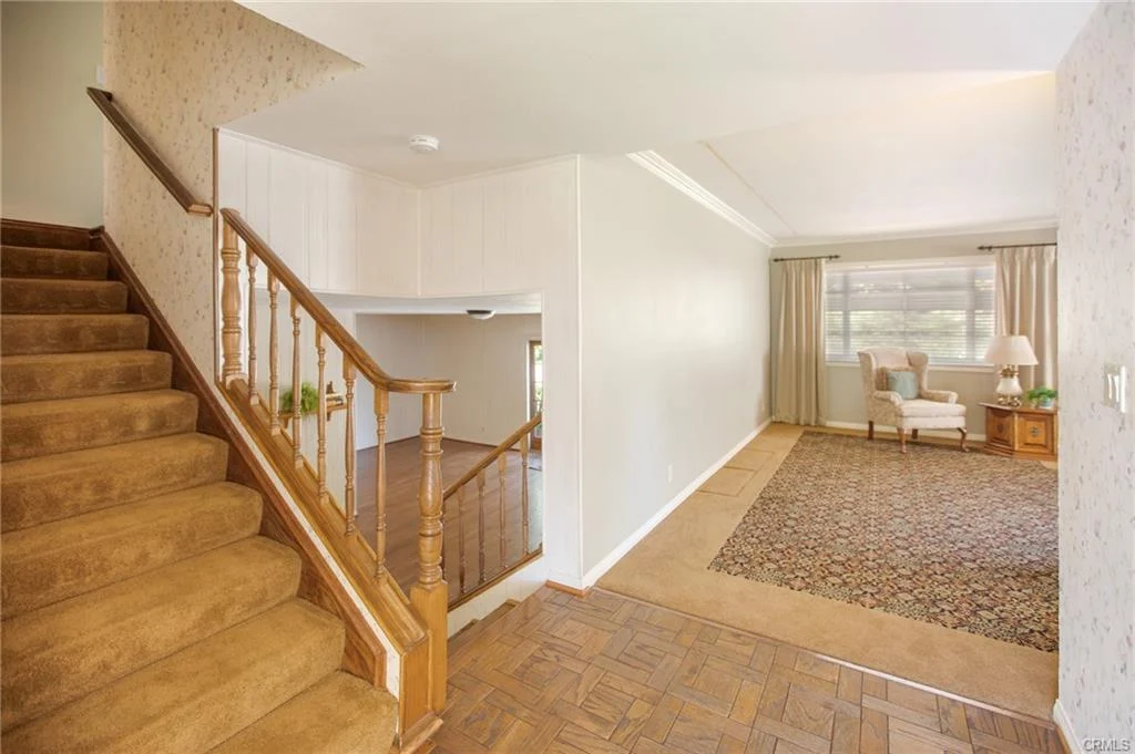 Entryway with staircase, living area, large windows, and patterned rug