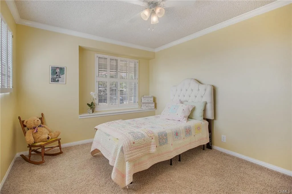 Bedroom with yellow walls, bed, and rocking chair.