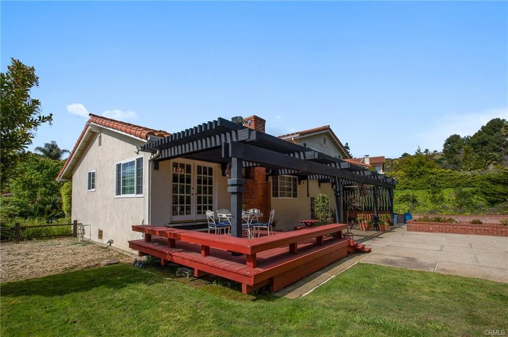 Backyard with wooden deck, seating, plants, and house, California real estate.