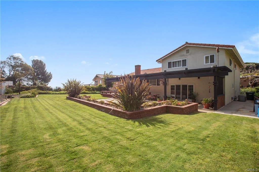 Backyard with lawn, patio, plants, and house, California real estate.
