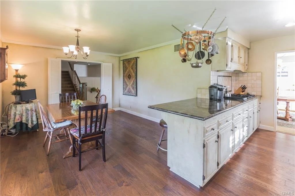 Kitchen with island, wooden floors, dining area, and staircase
