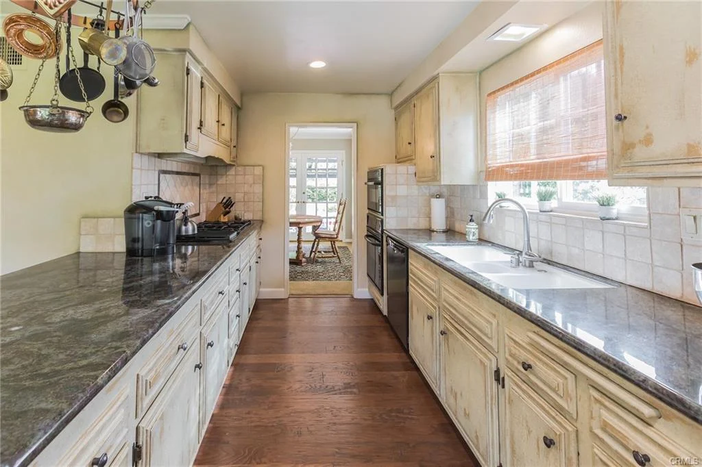 Kitchen with long granite countertop, wooden cabinets, sink, and appliances