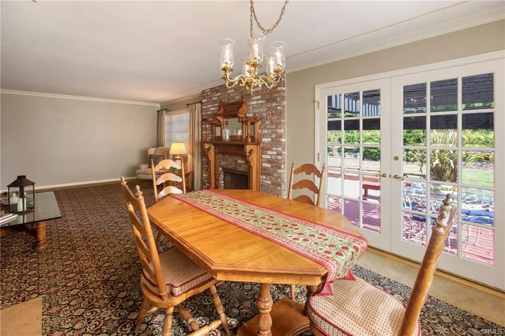 Dining room with wooden table, chairs, and fireplace leading to outdoor area