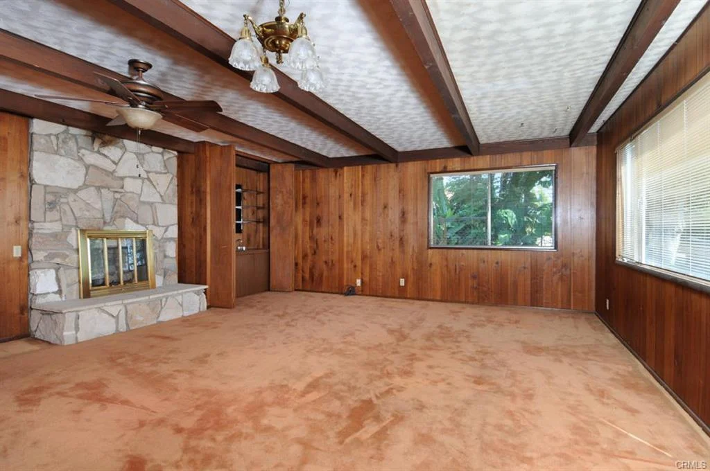 Room with wood walls, beams, fireplace, window, and carpet