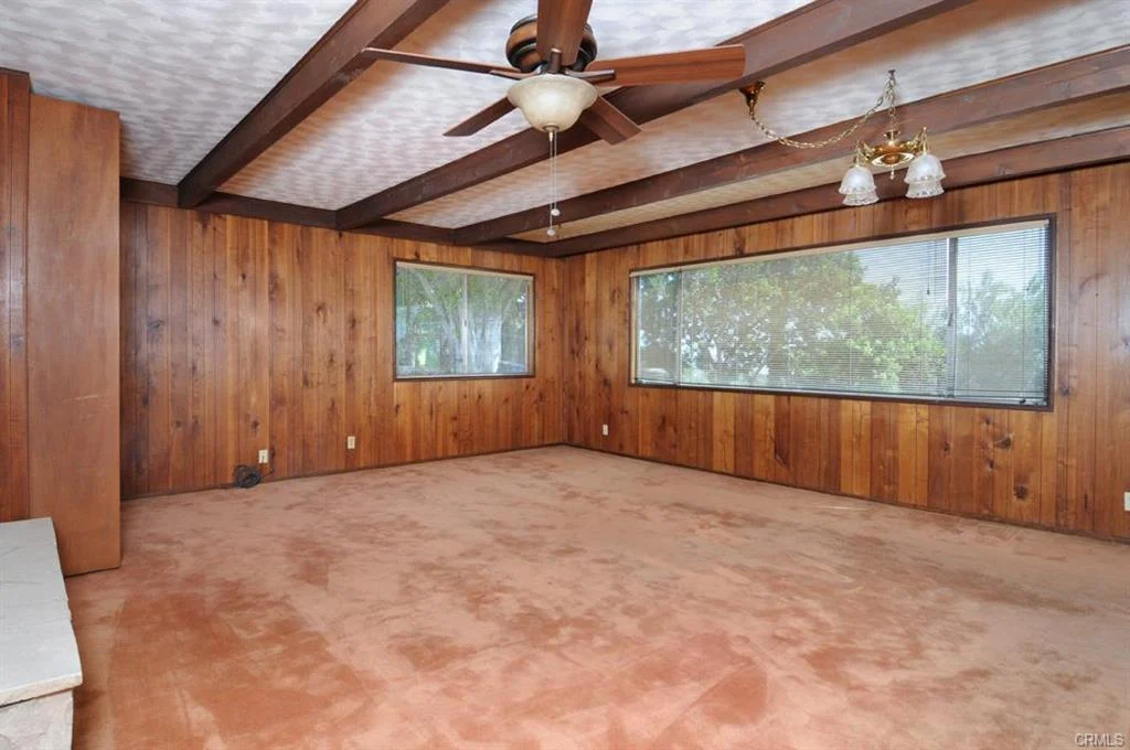 Room with wood walls, windows, ceiling fan, and carpet