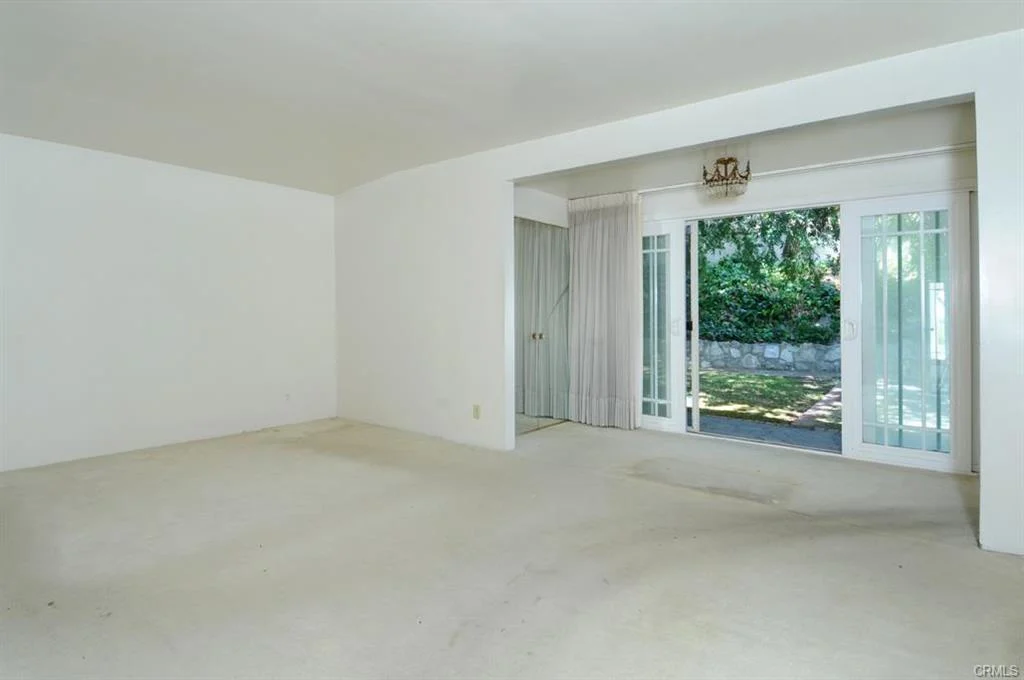Living room with carpet, walls, sliding door, and greenery outside