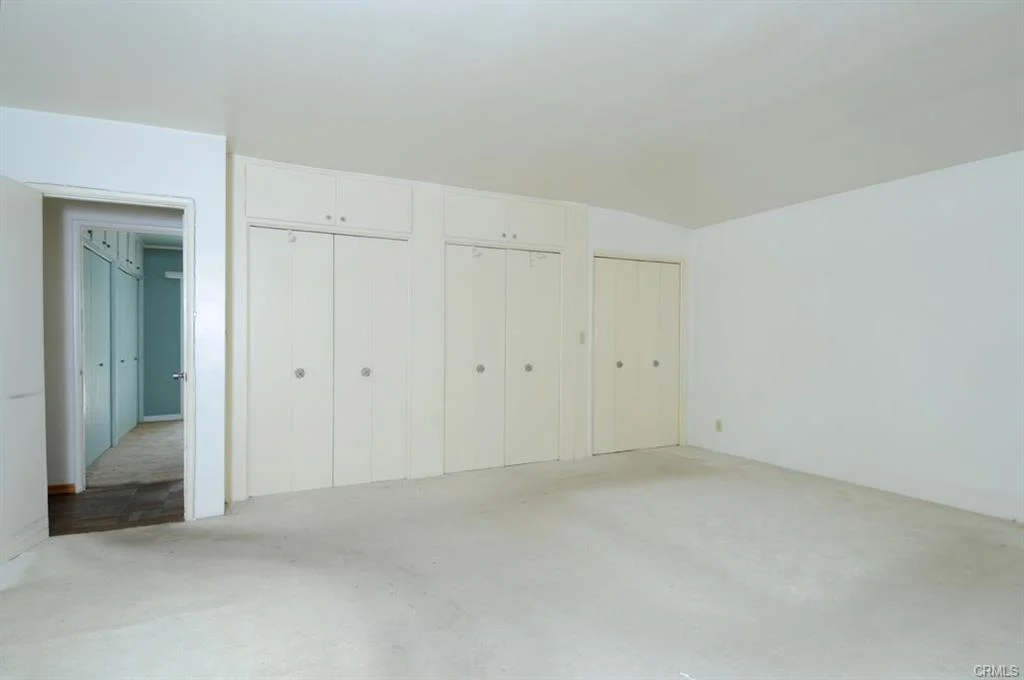 Empty room with white walls, closet doors, and doorway